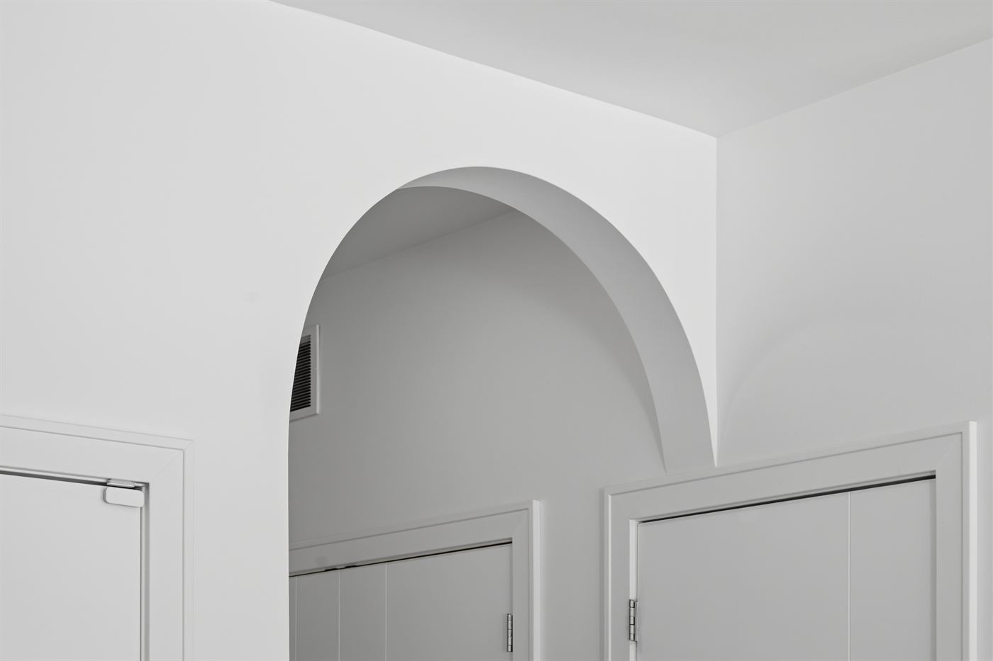 Arched plaster opening framing a hallway in white oak