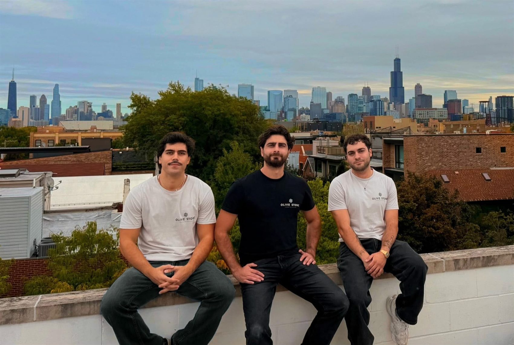 Lis, Paul-Joe and Sammy — the Olive Stone team — on a Chicago rooftop with the city skyline behind them